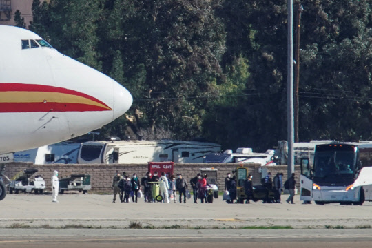 중국 우한에 머물던 미국인들이 29일(현지시간) 미국 정부가 보낸 전세기편으로 캘리포니아 주 리버사이드 카운티의 마치 공군기지에 도착한 뒤 대기중인 버스에 탑승하고 있다. 리버사이드 카운티=로이터 연합뉴스